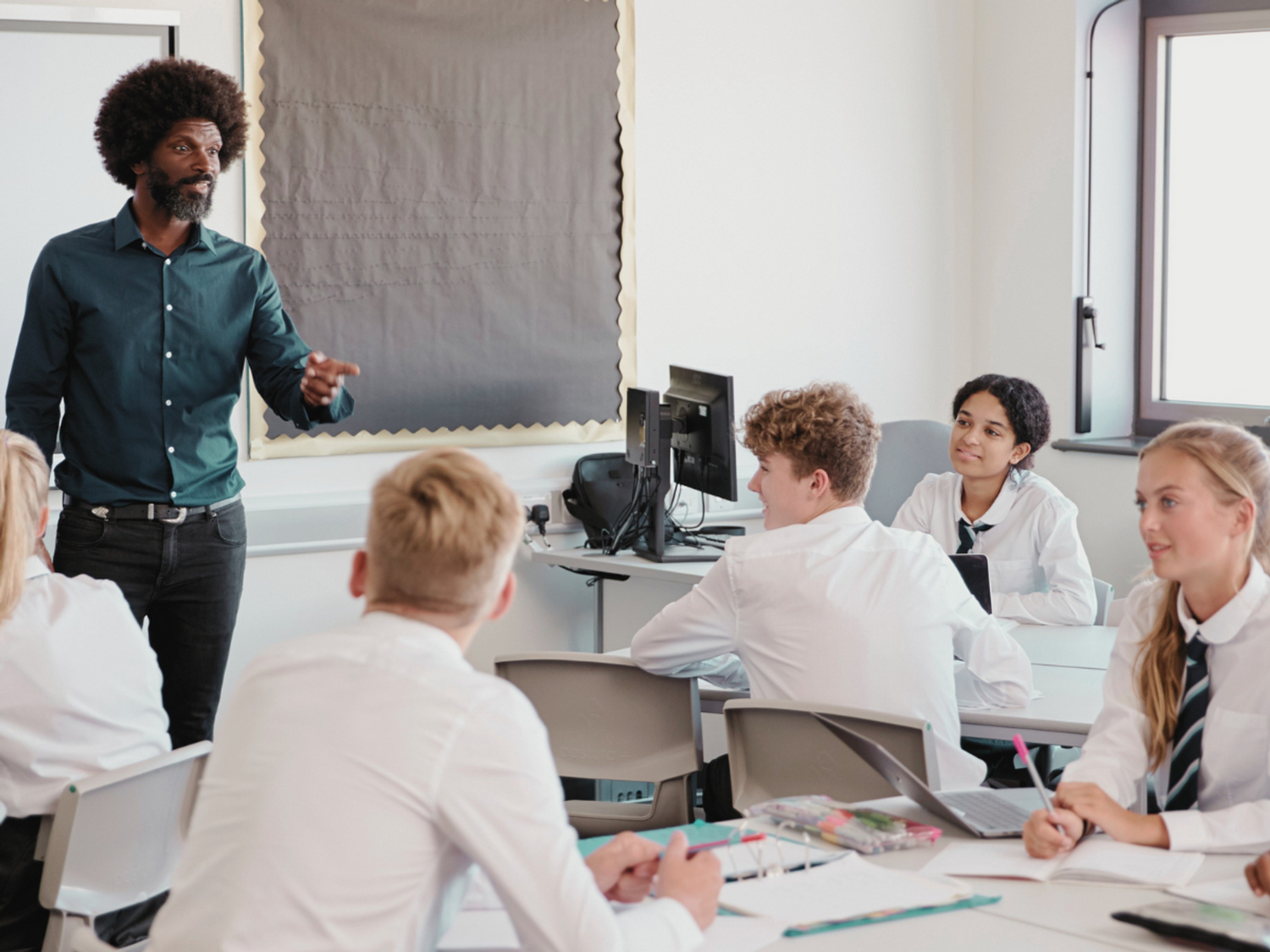 A teacher teaching a class of students on an interactive whiteboard