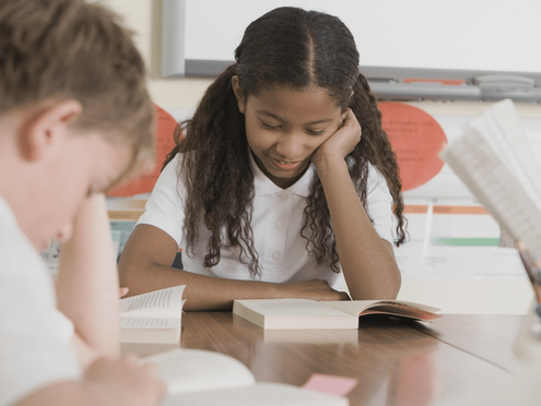 Two learners reading across the table from one another.