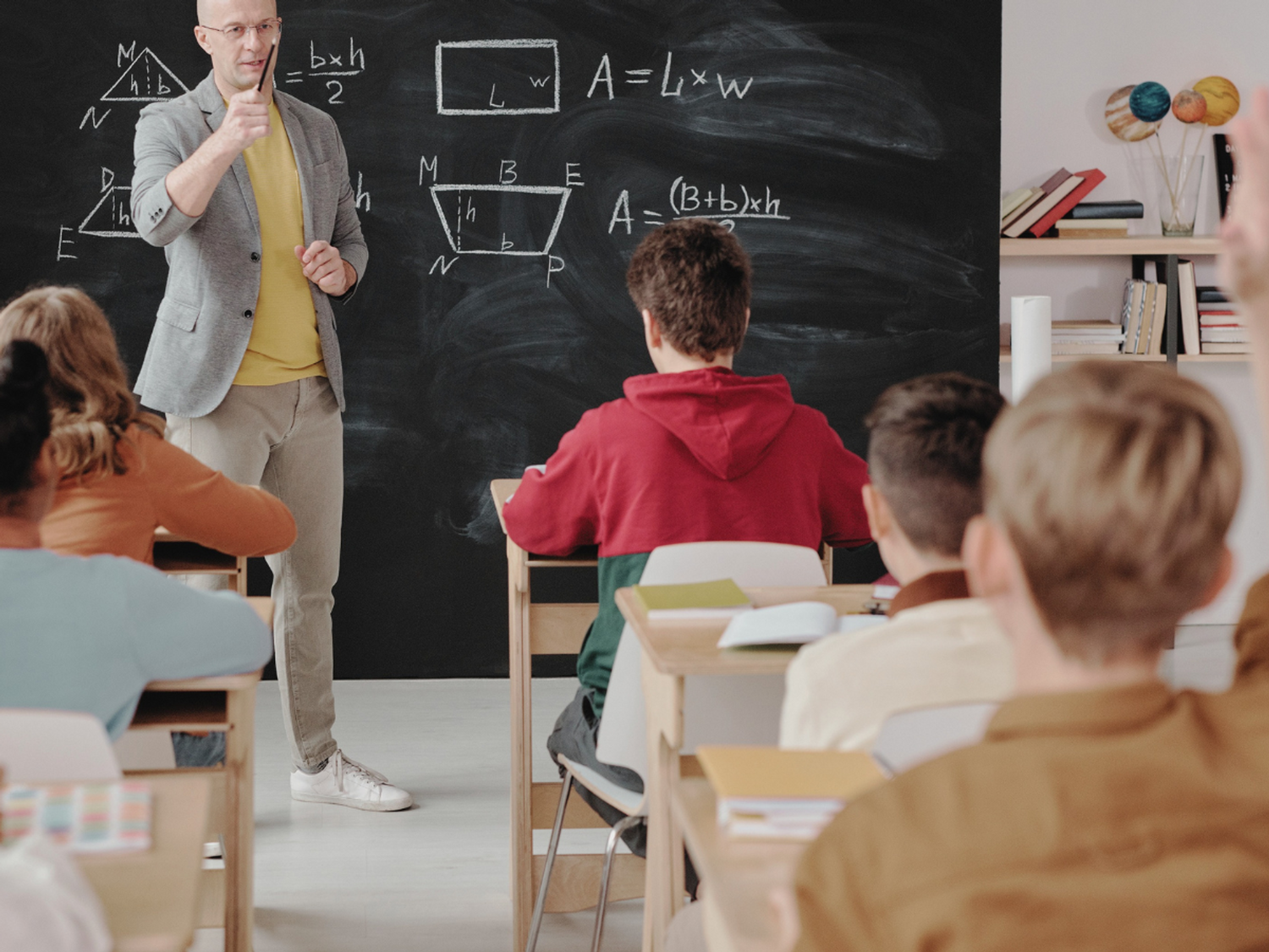 A student putting their hand up in a classroom.